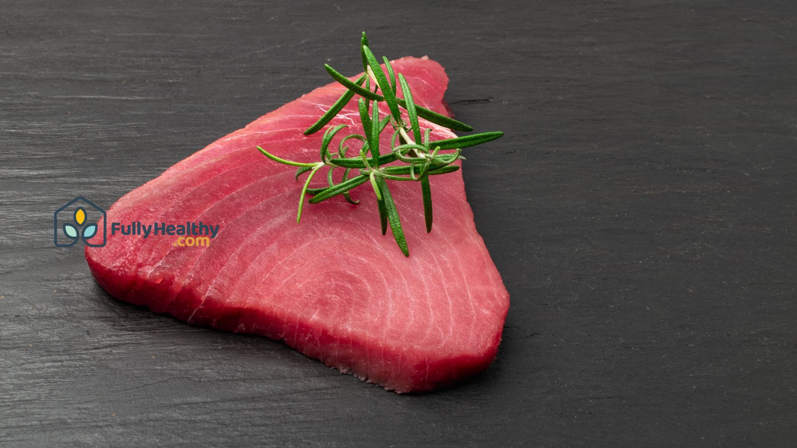 Raw tuna steak with rosemary herb on slate surface for meal prep