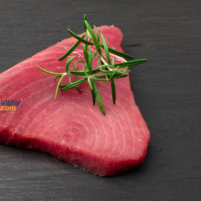 Raw tuna steak with rosemary herb on slate surface for meal prep