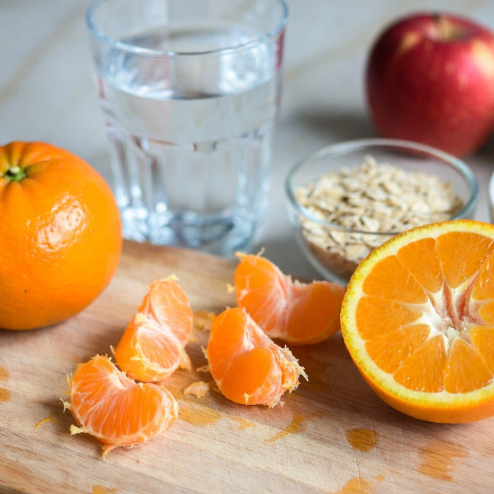 Fresh orange slices and whole oranges with oats and berries on board
