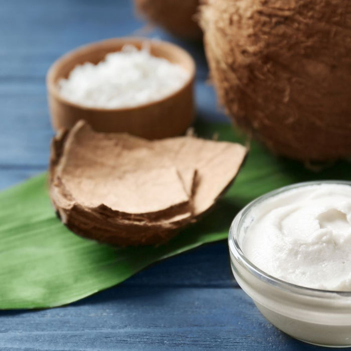 Fresh coconut cream in glass bowl with coconuts and leaf background