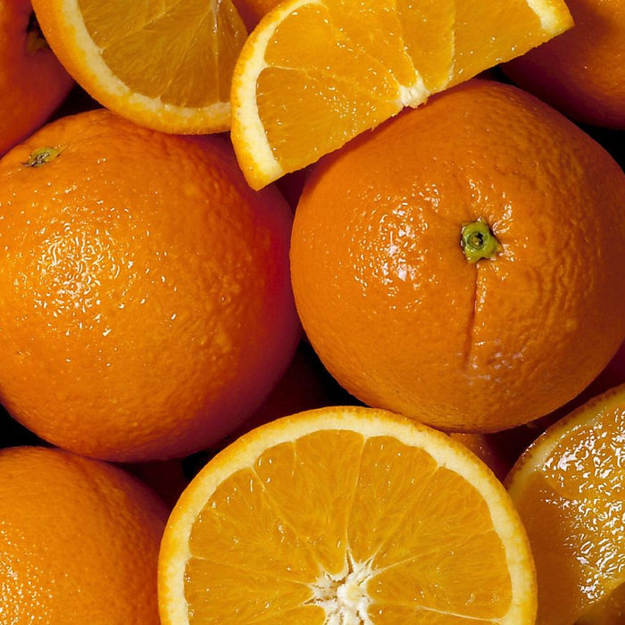 Fresh whole and sliced oranges stacked together for display.