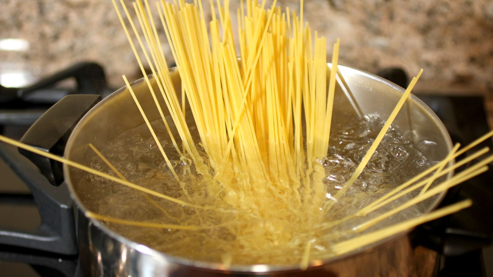 Spaghetti boiling in a pot of water on stovetop.