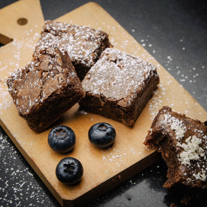 Brownies with powdered sugar and blueberries on wood board