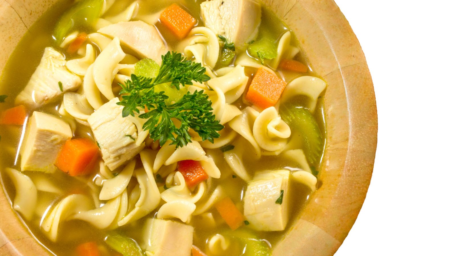 Chicken noodle soup in a wooden bowl with fresh parsley garnish