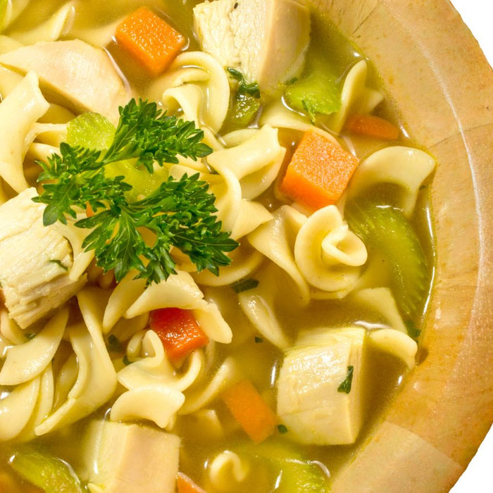 Chicken noodle soup in a wooden bowl with fresh parsley garnish