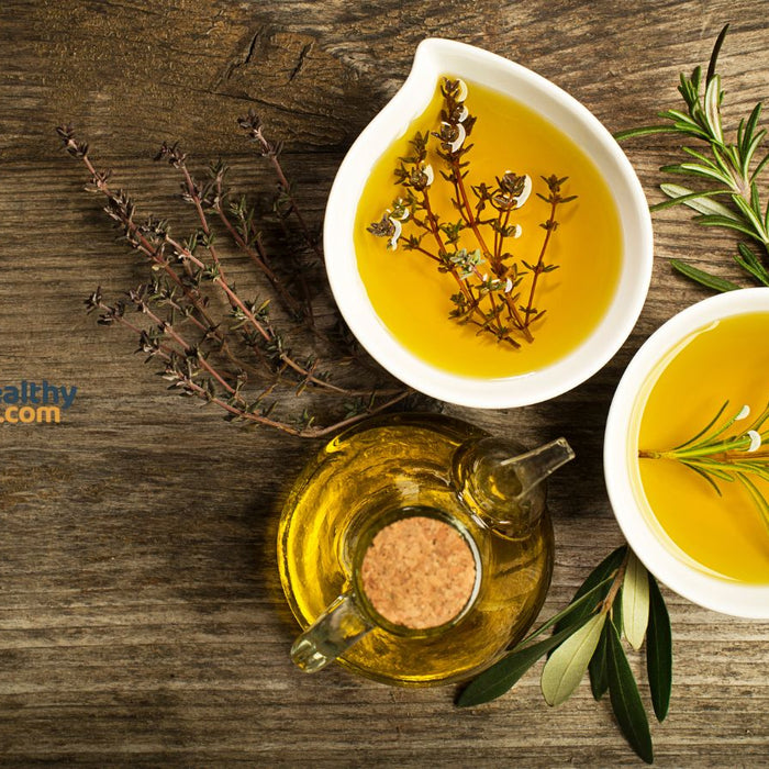 Bowls of olive oil with herbs on wooden table for healthy cooking.