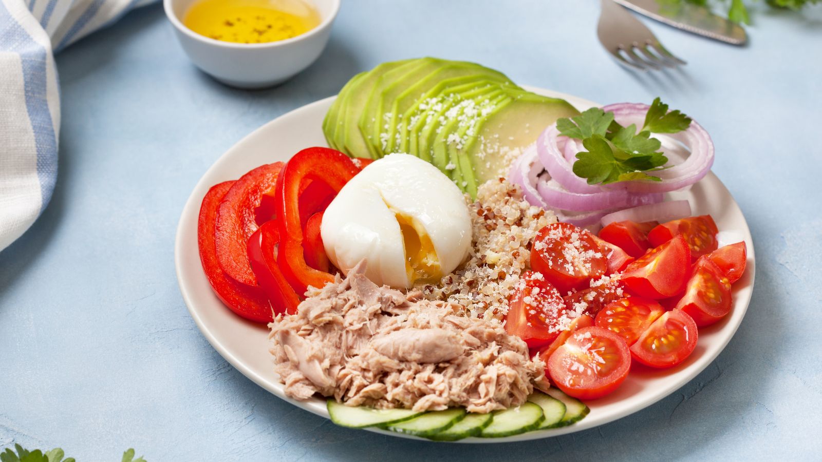 Healthy tuna salad bowl with avocado, egg, tomatoes, and quinoa.