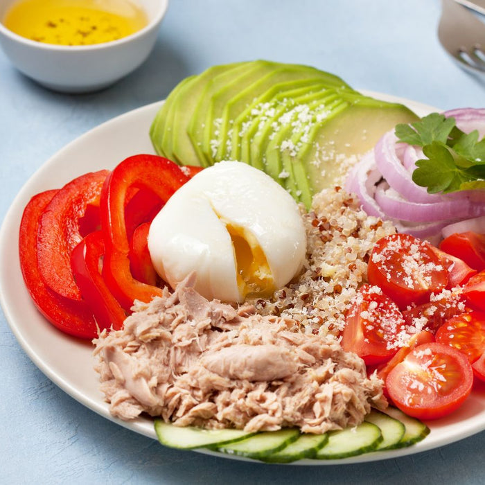 Healthy tuna salad bowl with avocado, egg, tomatoes, and quinoa.