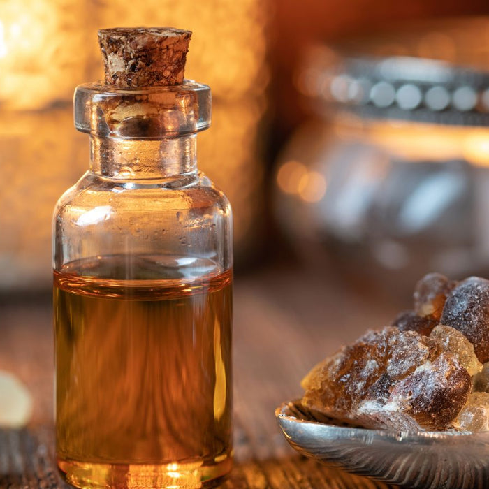 Small bottle of Frankincensel oil with resin pieces on a wooden surface.
