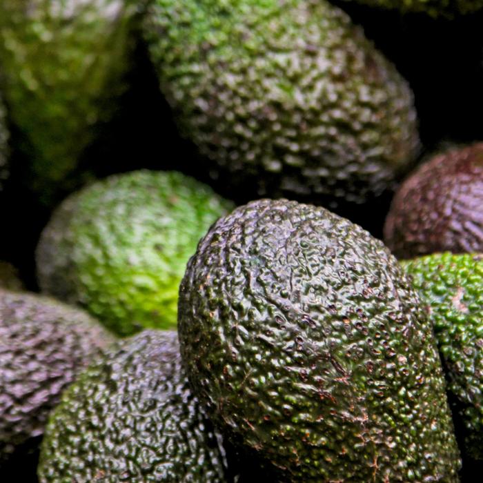 Close-up of fresh Hass avocados with dark bumpy green skin texture.