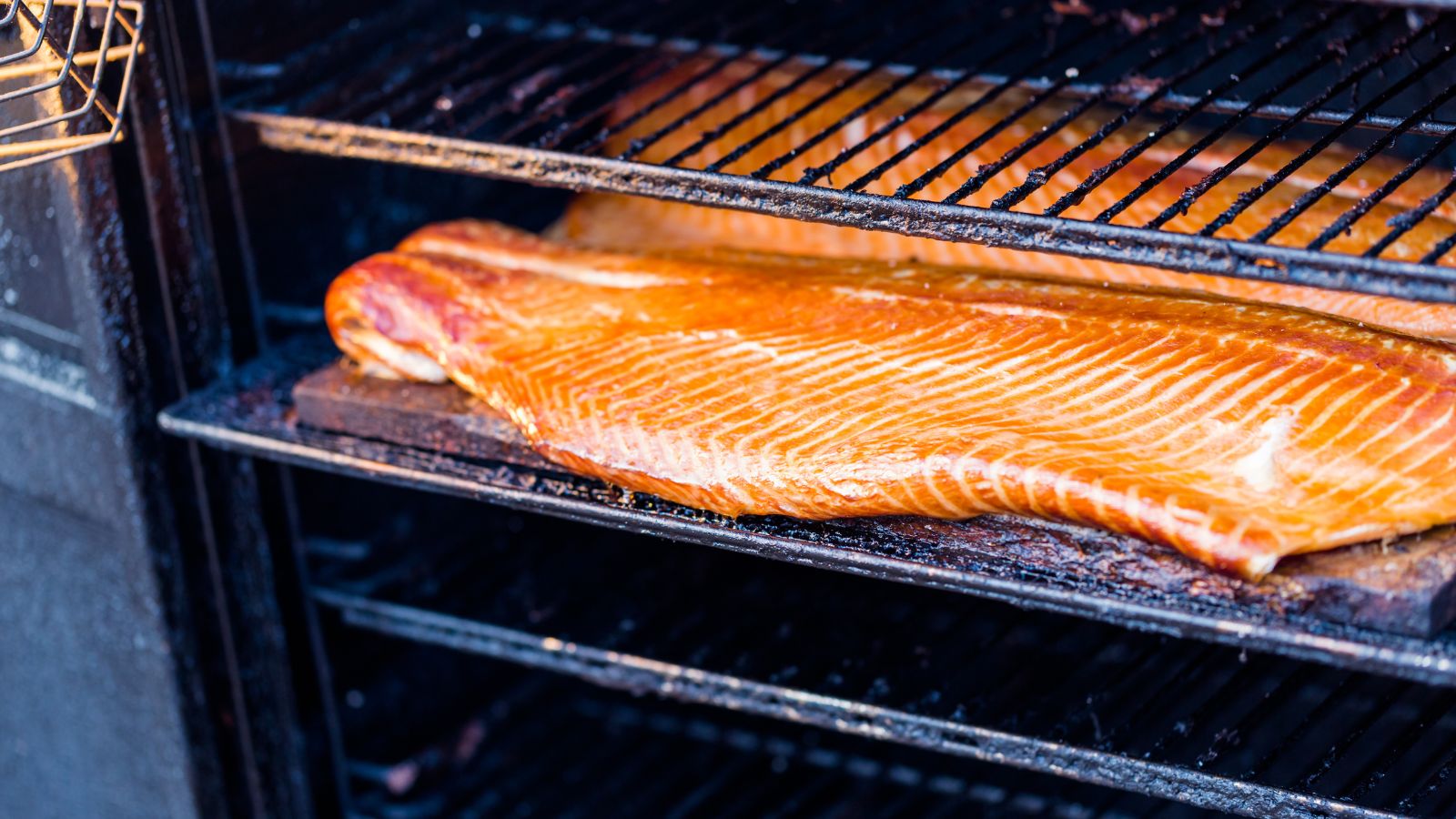 Smoked salmon on grill rack with golden-brown glaze.