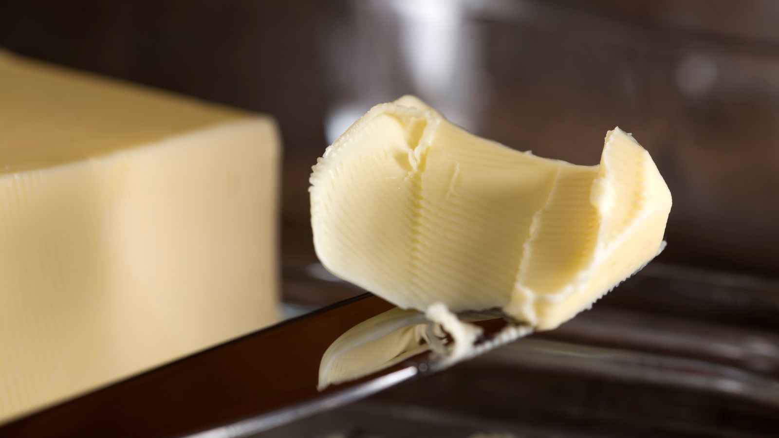 Block of butter with knife on a metal tray over a folded napkin.