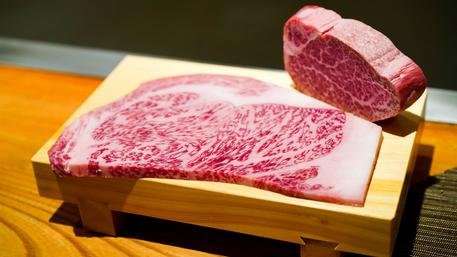 Wagyu beef steak with rich marbling on wooden tray.