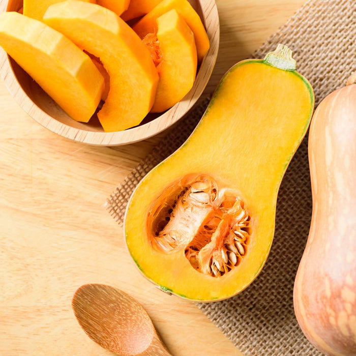 Sliced and whole butternut squash on wooden surface.