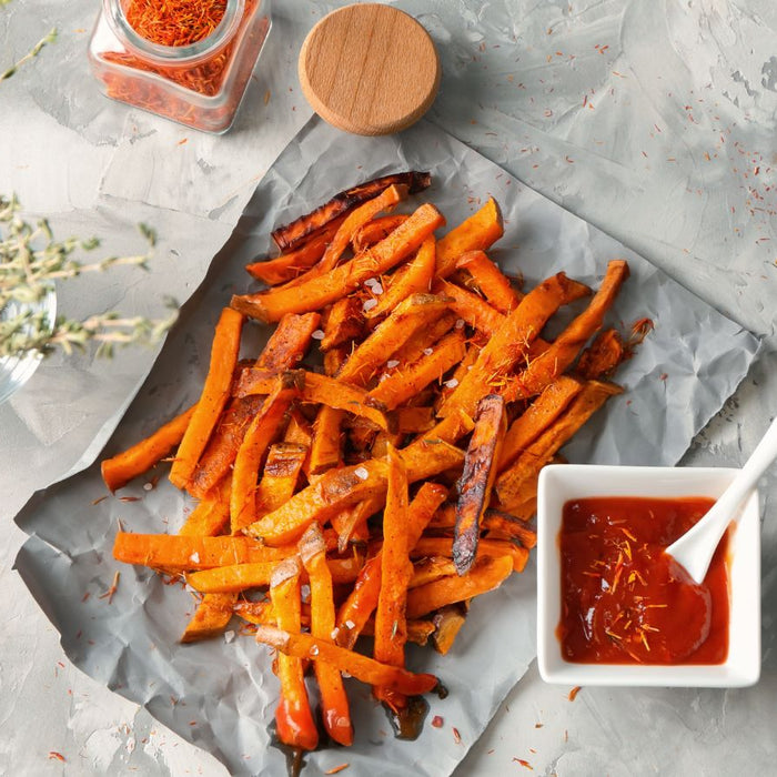 Sweet potato fries on parchment paper with tomato dipping sauce.