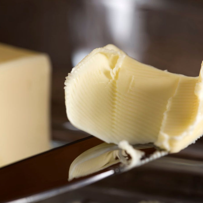 Block of butter with knife on a metal tray over a folded napkin.