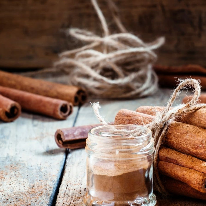 Jar of cinnamon powder and tied sticks on rustic table.