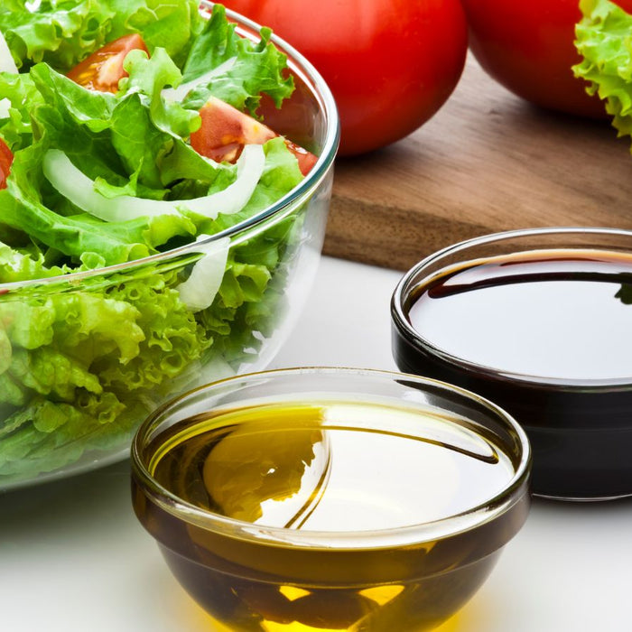 Fresh salad with tomatoes and onions beside oil and vinegar.