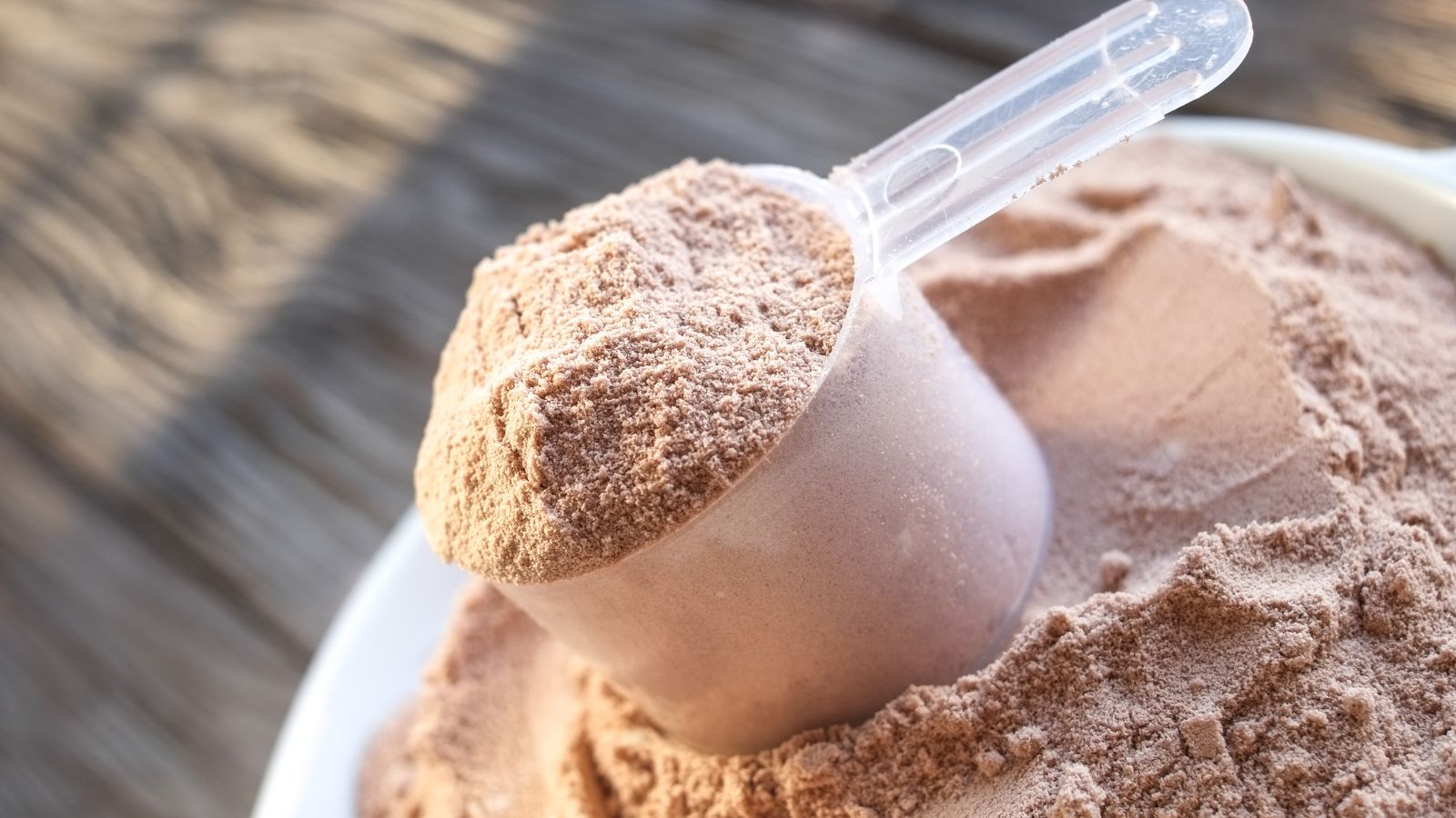 Scoop of chocolate protein powder in a white bowl.