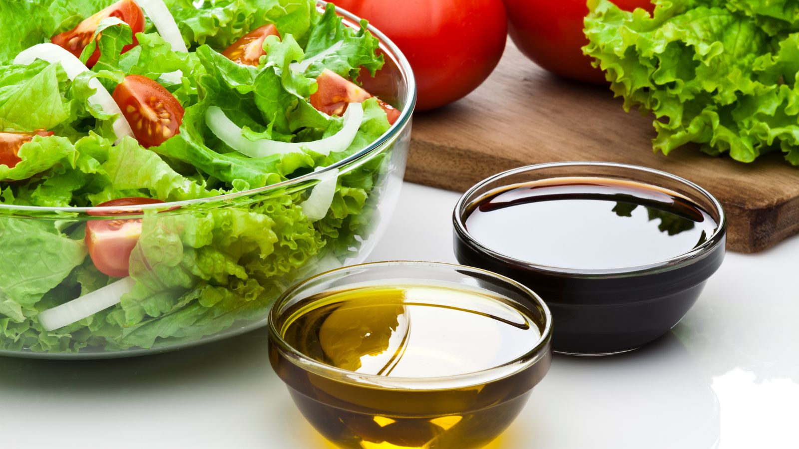 Fresh salad with tomatoes and onions beside oil and vinegar.