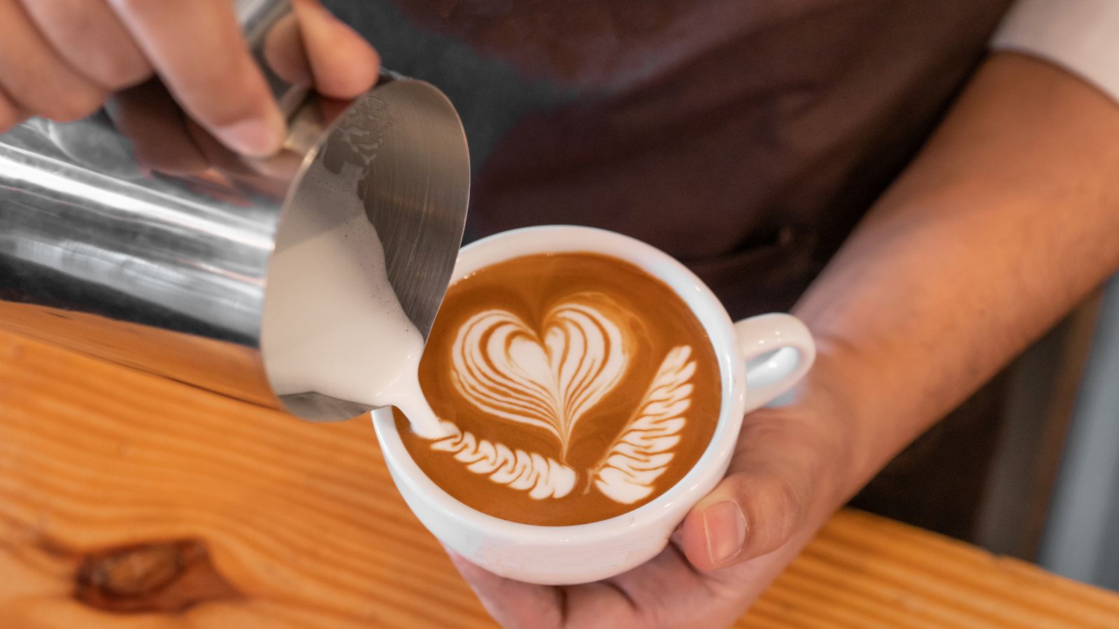 Latte art heart design being poured into a cup of coffee