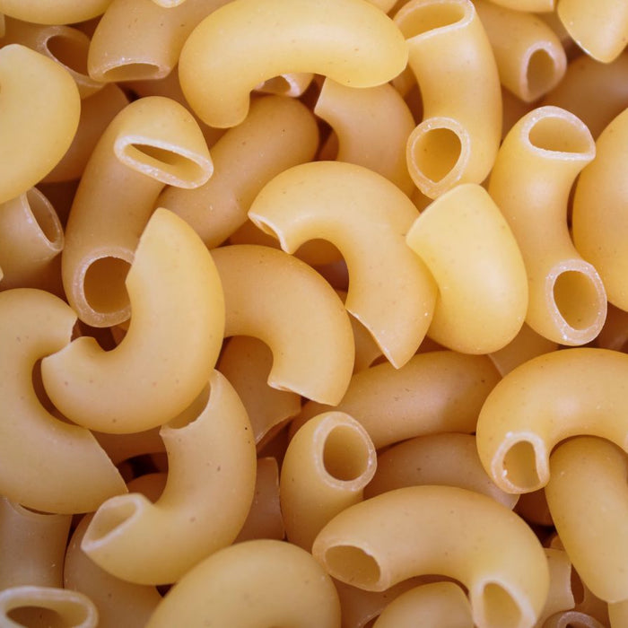 Close-up of uncooked elbow macaroni pasta in a tight cluster.