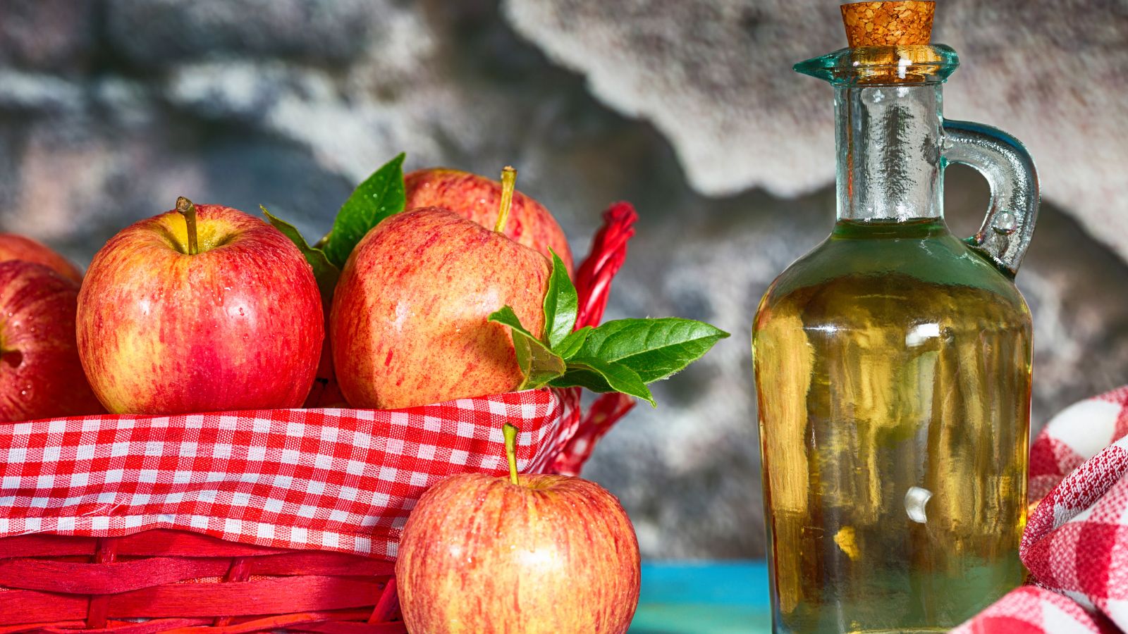 Fresh red apples in a basket with apple cider vinegar bottle beside