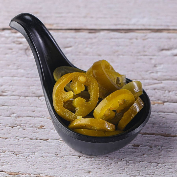 Bowl of sliced pickled jalapeños on rustic white surface