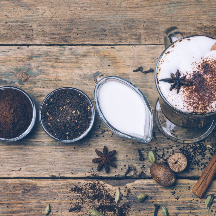 Dirty Chai latte with spices and ingredients on rustic wooden table.