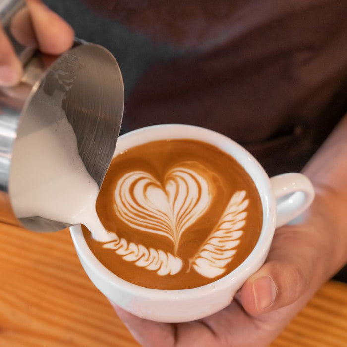 Latte art heart design being poured into a cup of coffee