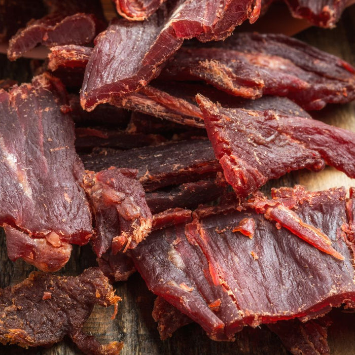 Dried beef jerky slices on a rustic wooden surface.