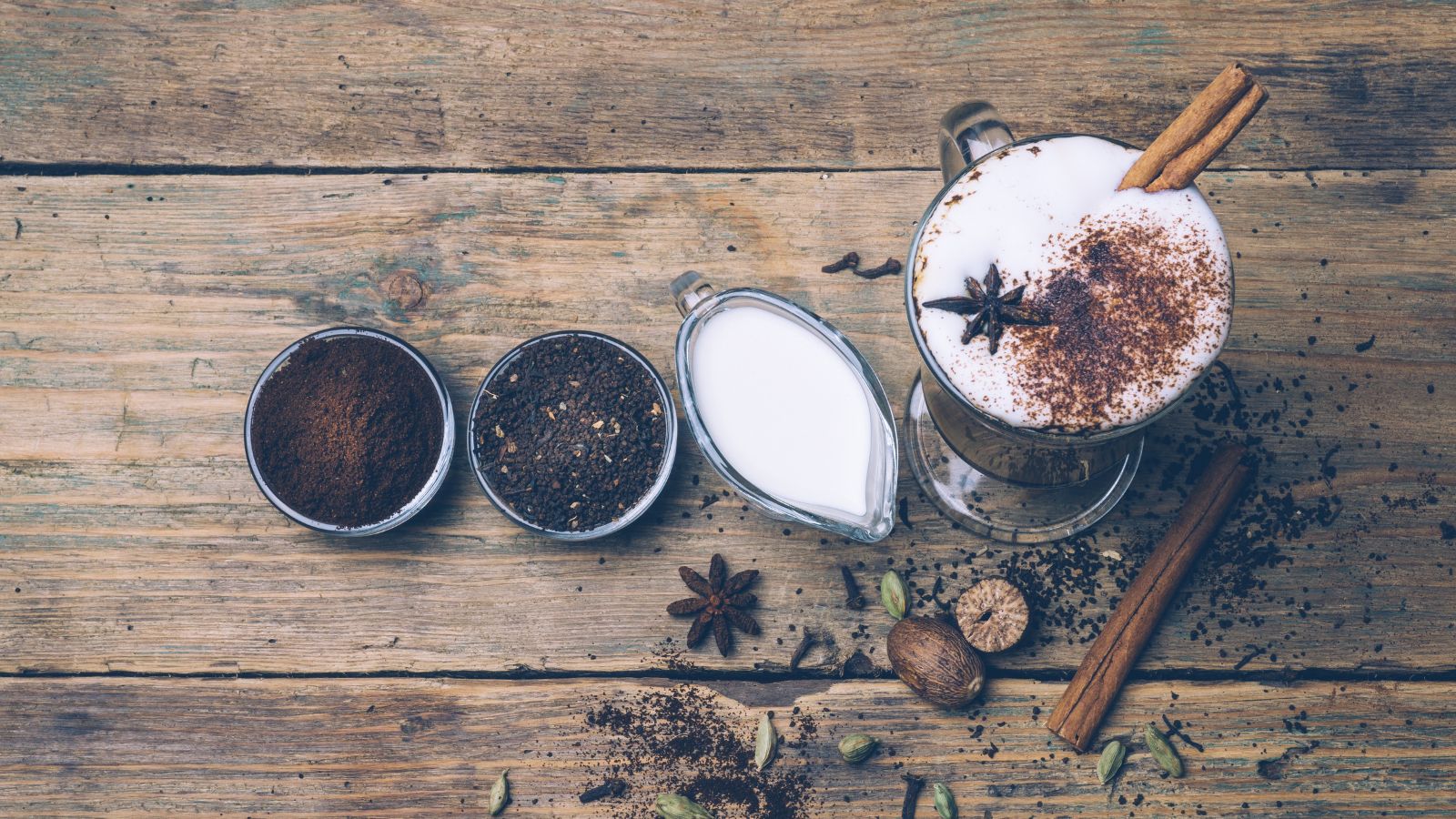 Dirty Chai latte with spices and ingredients on rustic wooden table.