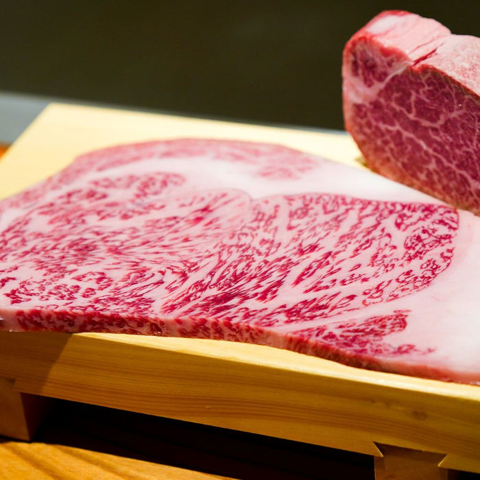Wagyu beef steak with rich marbling on wooden tray.