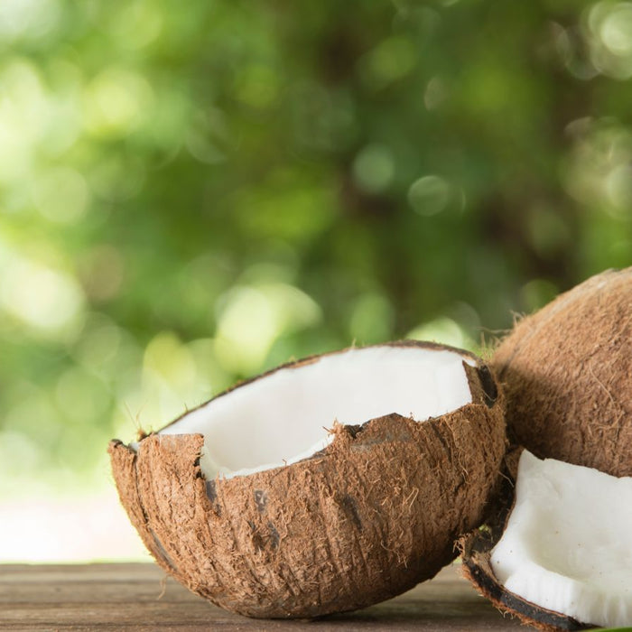 Fresh brown coconuts cracked open on wooden table outdoors