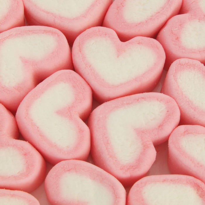 Heart-shaped pink and white candies with a soft texture, arranged closely together.