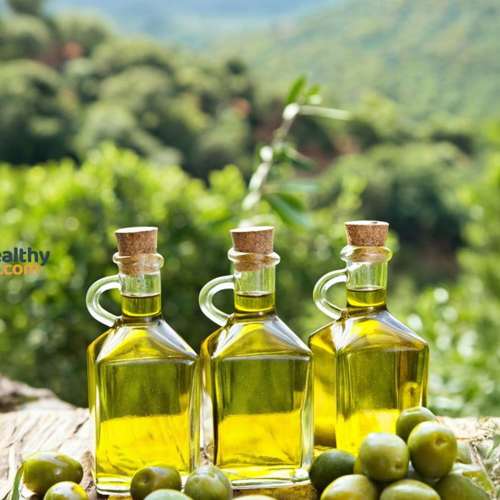 Bottles of olive oil with olives outdoors in natural green background.