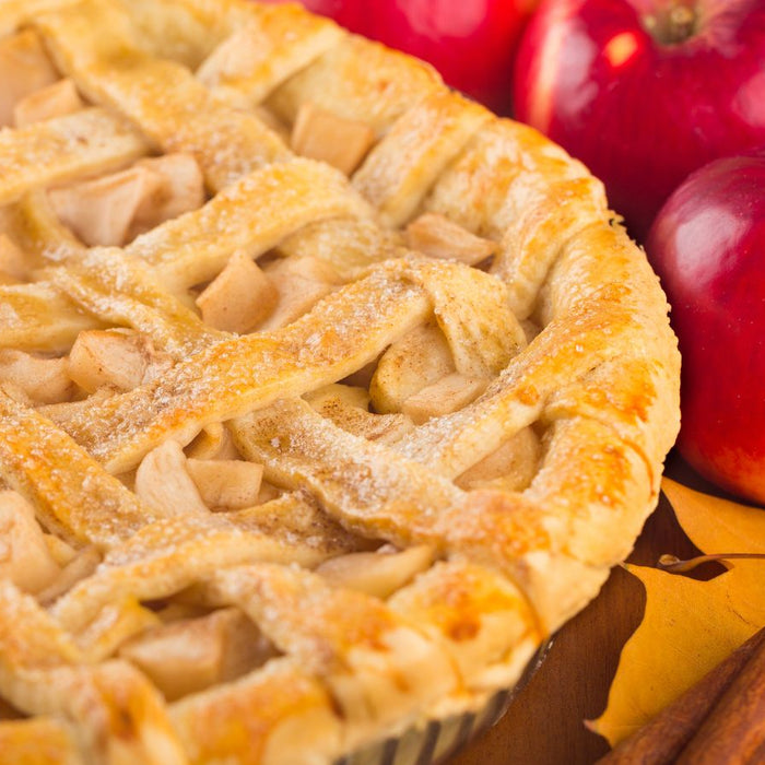 Homemade apple pie with cinnamon sticks and red apples on the table