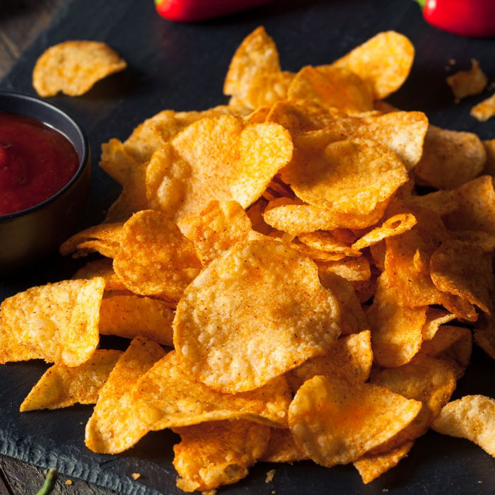 Spicy potato chips served with a side of red dipping sauce and chilies