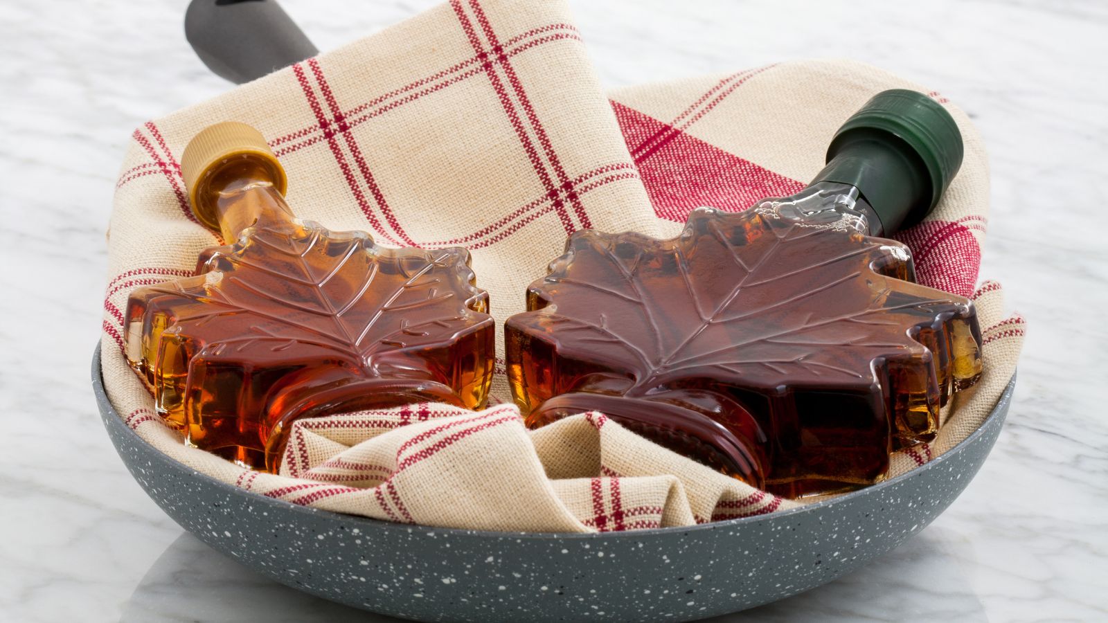 Maple syrup in decorative leaf-shaped bottles with fabric napkin.