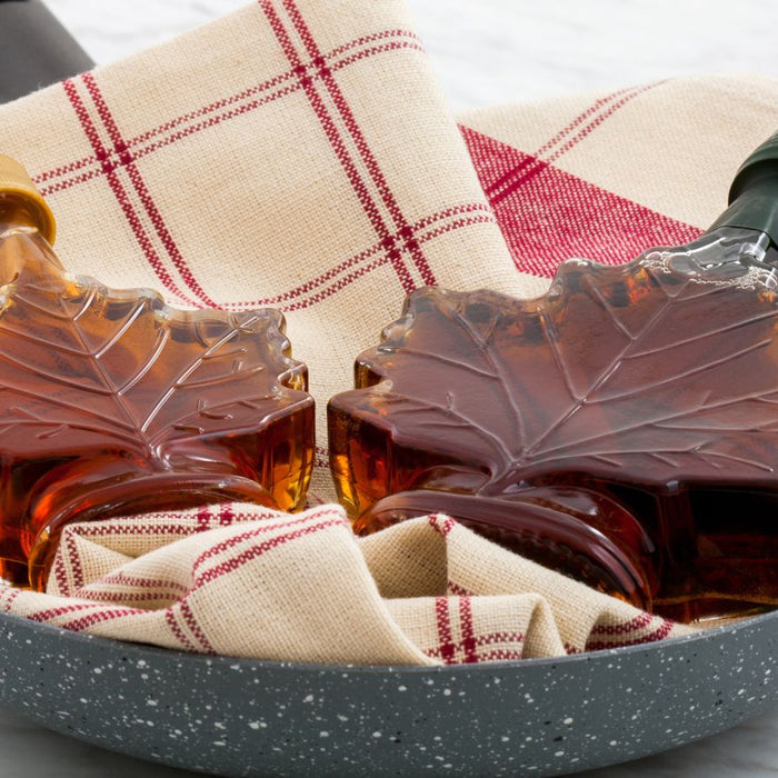 Maple syrup in decorative leaf-shaped bottles with fabric napkin.