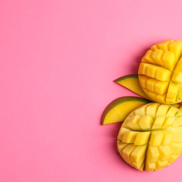 Three grid-cut mango halves arranged on pink background.