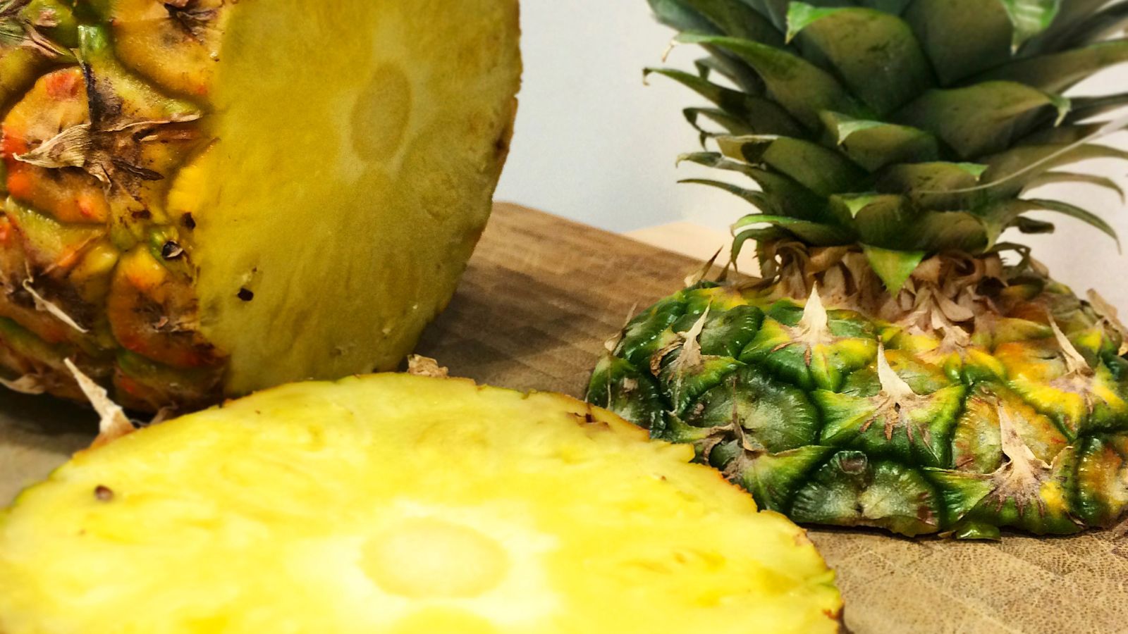 Sliced and whole pineapples on a cutting board.