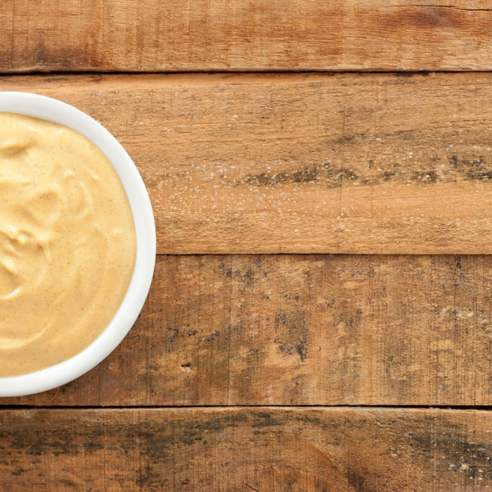 Creamy dijon mustard in a white bowl on wooden table.