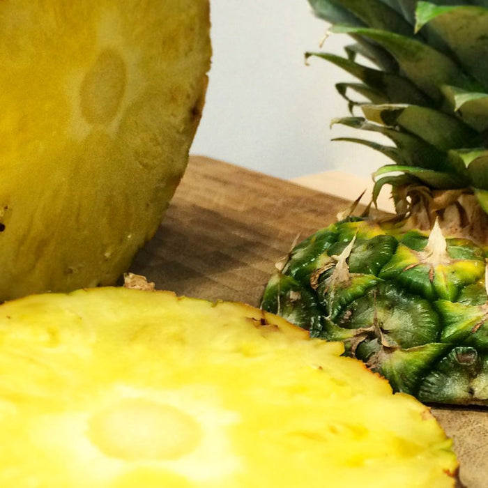 Sliced and whole pineapples on a cutting board.