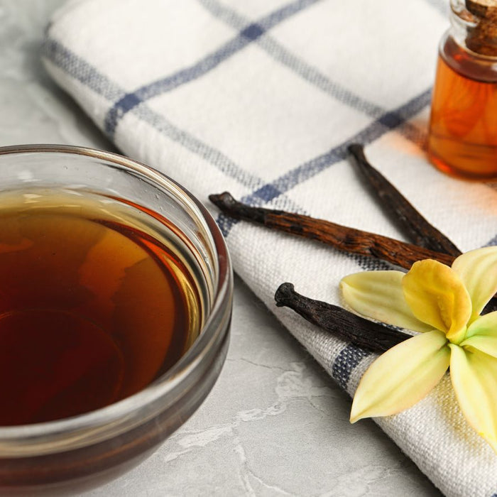 Vanilla extract with pods and flower on cloth.