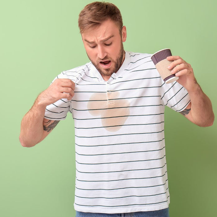 Man shocked by turmeric stain on white shirt against green background