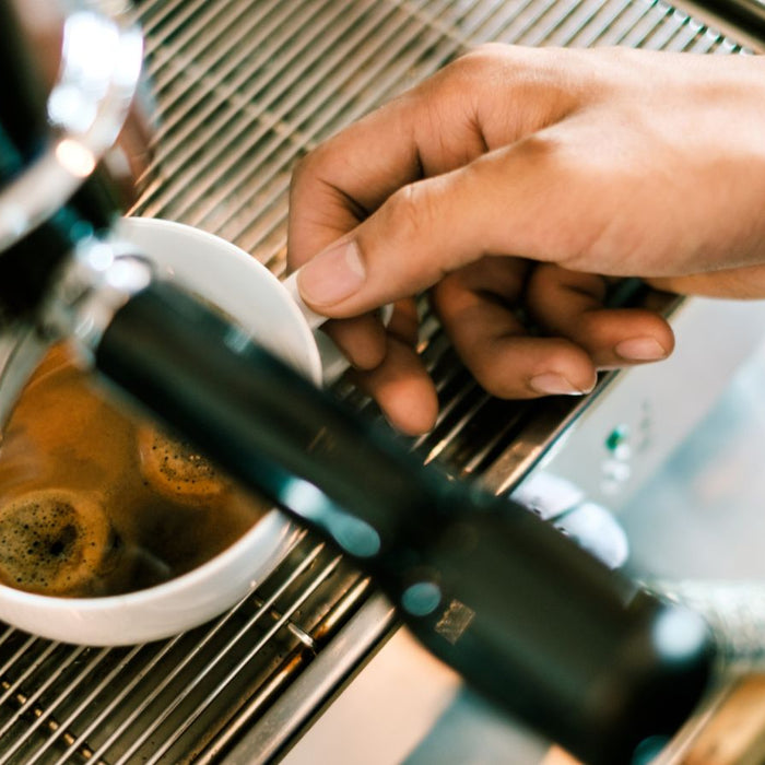 Espresso shot being pulled with a hand adjusting the cup