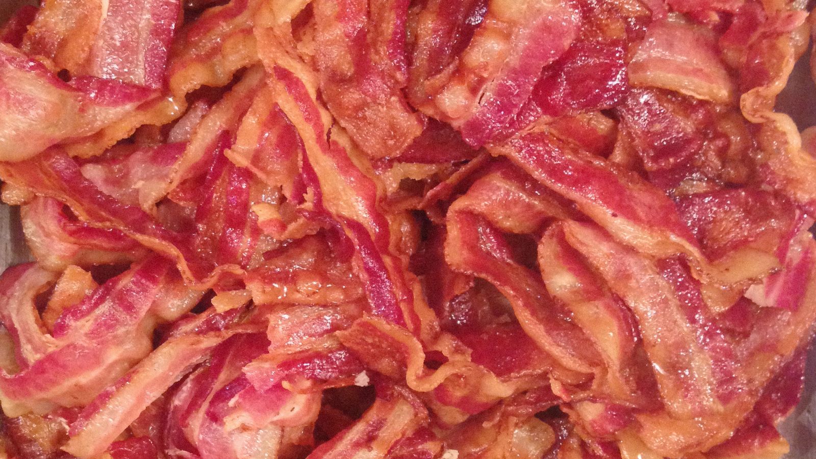 Crispy fried uncured bacon served on a wooden cutting board.