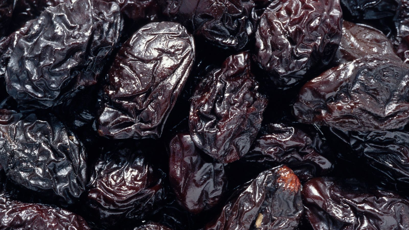 Close-up of wrinkled dried prunes piled together.
