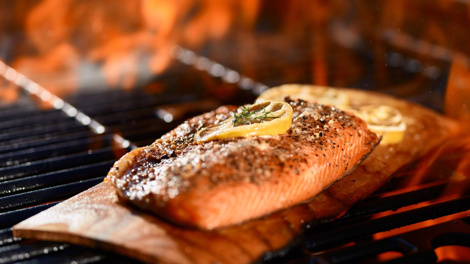 Cooked salmon fillet with lemon slices on cedar plank.